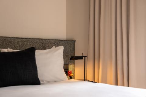 Doppelbett im Hotelzimmer mit verschiedenen Kissen und einem Nachttisch