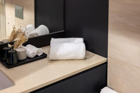 Aufgerollte Handtücher und Dekoration im Badezimmer eines Hotels