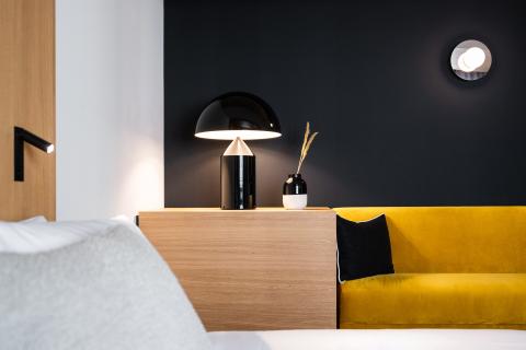 Kleine Lichter fallen ins Hotelzimmer mit Doppelbett und gelbem Sofa