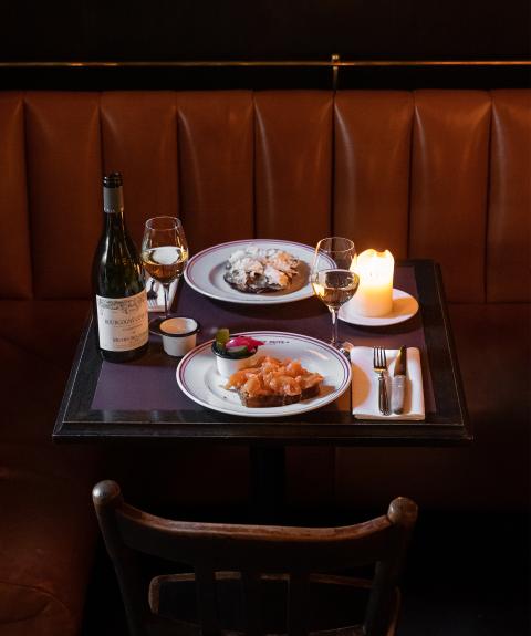 Ein gedeckter Tisch für zwei Personen mit Weißwein, Fischgerichten und einer Kerze