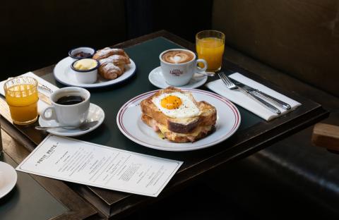 Ein gedeckter Tisch für zwei Personen mit einem Frühstück aus Toast, Eiern, Süßgebäck und Kaffee