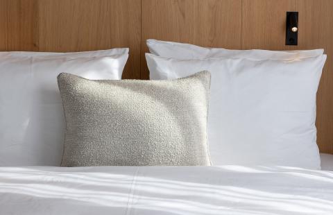 Details eines Bettes im Hotel Schwabing mit weißen und grauen Kissen