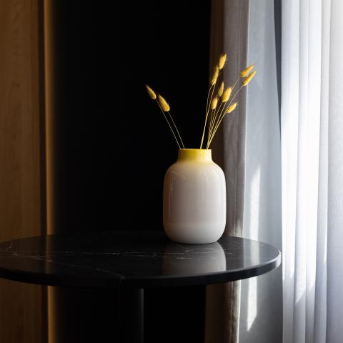 Ein runder schwarzer Tisch mit einer Vase vor dem Fenster eines Hotelzimmers in Schwabing