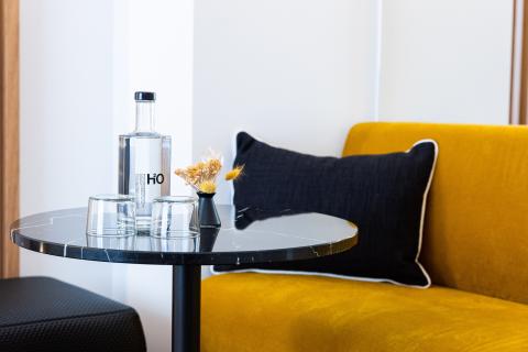 Ein gelbes Sofa mit einem Marmortisch und zwei Gläsern neben einer Wasserflasche