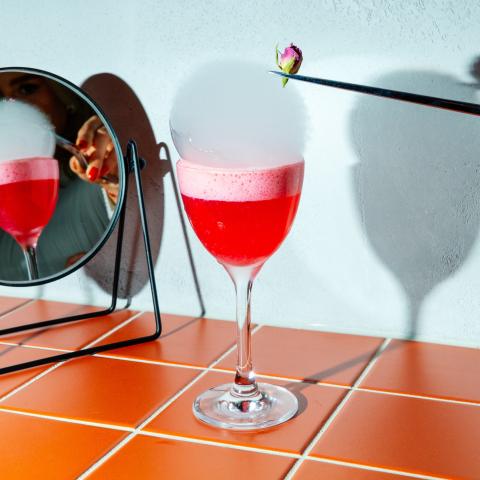 Red cocktail with foam and decorative flower