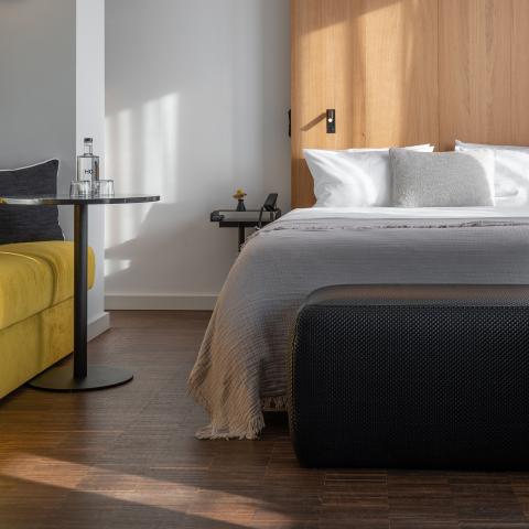 Hotelzimmer des Hotels in Schwabing mit Doppelbett, gelbem Sofa und einem Beistelltisch