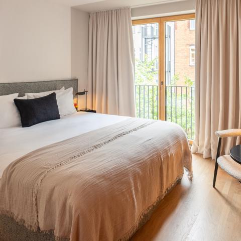 Large double bed in a bright hotel room overlooking the courtyard